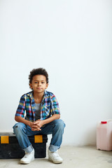 Young boy sitting on tool-box after relocation to new flat