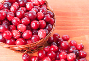 Fresh cranberries in a small basket on a wooden background