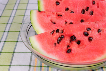 Slices of ripe red watermelon lying in a transparent plate