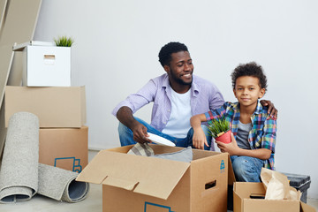 Father and son unpacking carton boxes after relocation