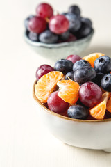 Plate with fruit salad of mandarin, grape, blueberry. Delicious