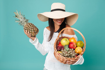 Young lady over blue background holding basket with fruit
