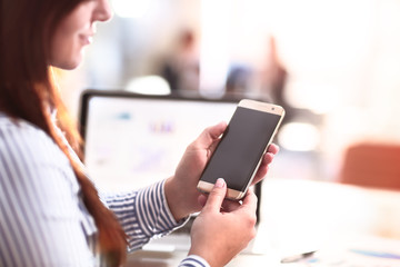 Woman typing text message on smart phone in office
