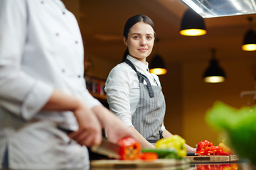 Young staff of restaurant cooking vegetables - obrazy, fototapety, plakaty