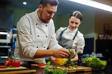Poster Chef and his trainee cooking vegetable salad © pressmaster