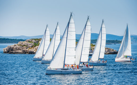 Group of sailing boats during race. Small island in background.