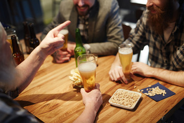 Snack and beer on table and hands of men during talk