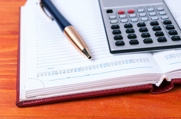 Calculator and pen lie on open diary. Business concept
