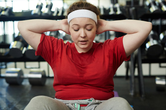 Portrait of young obese woman doing sit up exercises while working out in  gym, breathing heavily with effort and sweating foto de Stock | Adobe Stock