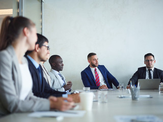 Group of people in formalwear having discussion of modern business at meeting