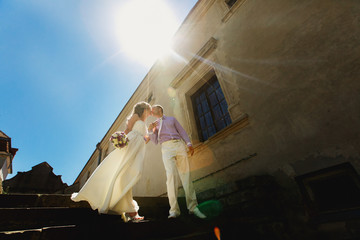 Sun sparkles over kissing newlyweds standing on footsteps on the backyard