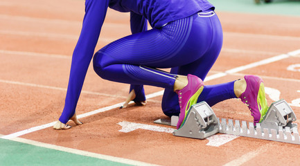 Sportswoman at the starting blocks before sprint running event