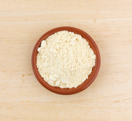 Top view of soy powder in a small bowl on a wood table.