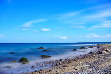 Fototapeta na wymiar Langzeitbelichtung Strand mit Steinen und blauem Himmel