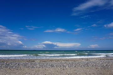 weiter Strand mit Steinen, Meer und blauem Himmel