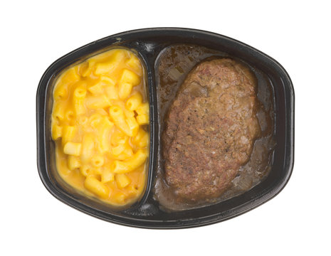 Top view of a Salisbury steak meal with macaroni and cheese TV dinner isolated on a white background.