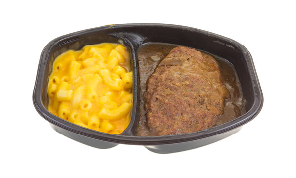 Salisbury steak meal with macaroni and cheese TV dinner isolated on a white background.