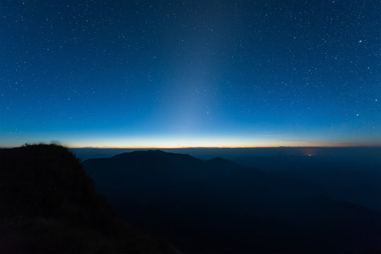 Stars illuminated above the dark silhouette mountain before sunrise. © chanwitohm