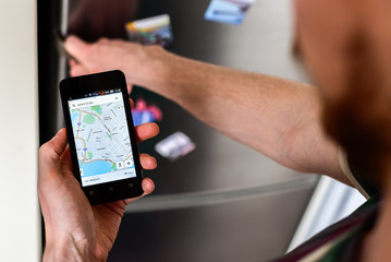 Person hands holding smartphone and searching for places to eat on map