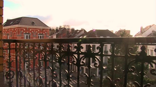 Balcony view on old town in Europe, gold sunset sky, dolly shot wrought iron fencing, lens flare