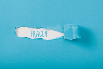 Fragen (German for questions) message on Paper torn ripped opening