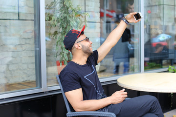 Young guy arab male man makes selfie, talks on Skype, smiles and