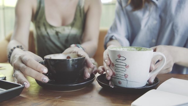 Two Woman Friends Sharing Coffee In Cafe