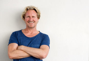 happy middle aged man posing with arms crossed against white background