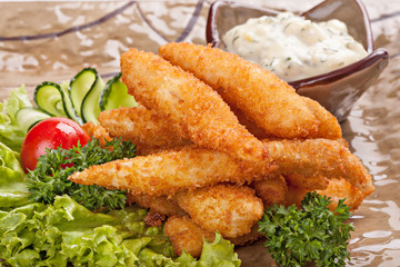 Pieces of fish fried in batter garnished with vegetables.