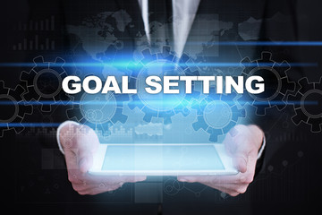 Businessman holding tablet PC with goal setting concept.
