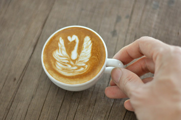 Barista hand holding cup of coffee with his latte art