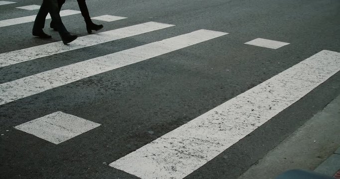Footage of people crossing a street on a pedestrian crossing.