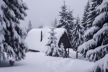 Old shelter in the winter mountains. Smoke comes from the chimney