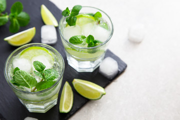 Cold refreshing summer lemonade mojito in a glass on a slate board and stone background.