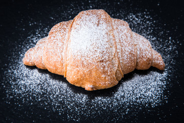 Fresh croissant on a black slate background. Top view