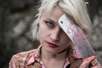 Russian young girl with blue eyes and blond hair with a bloody butcher knife in her hand. She is...