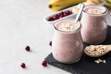 Smoothie of banana and cranberries with yogurt and oats on an slate Board