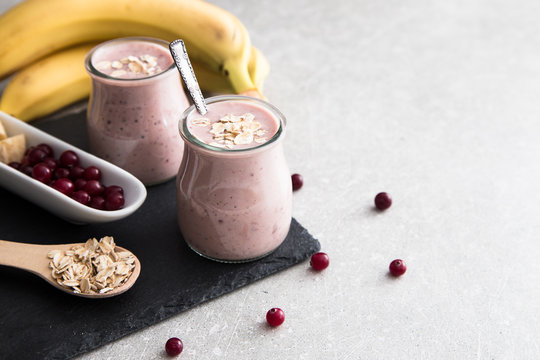 Smoothie of banana and cranberries with yogurt and oats on an slate Board