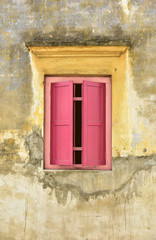 Fototapeta na wymiar Red wooden window on yellow wall