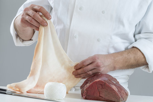 butcher preparing roast beef, with bard lard,