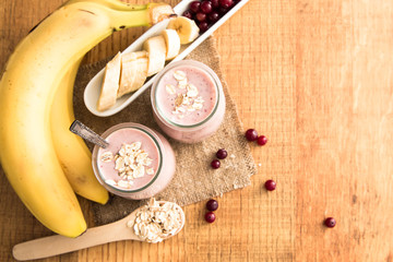 Smoothie of banana and cranberries with yogurt and oats on an old table