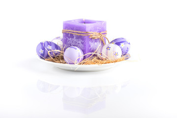 Easter background /
Violet candle and easter eggs on a white background