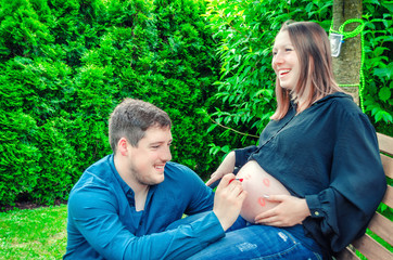 Pregnancy, parenthood and happiness concept. Family expecting baby. Future father  draws kiss on the stomach of his pregnant wife