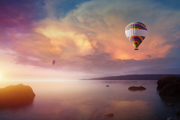 Two colorful hot air balloons flies in glowing sunset sky