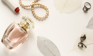 светлый фон с женскими духами в стеклянном красивом флаконе и украшениями  © danysharipova