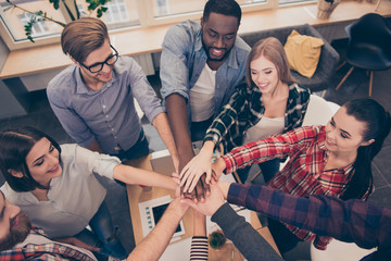 Creative multinational business team putting hands together at the office