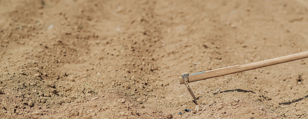 Freshly plowed field and mattock for manually planting in spring.
