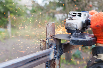 Closeup of a man using a grinder with cutoff blade to cut a section of pipe