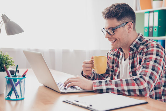 Happy smiling man drinking tea and working with laptop