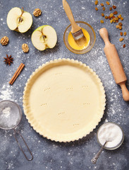 Work with the dough. Form for baking and ingredients for apple pie. The process of preparation of tart. View from above.